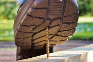 a closeup image of a shoe about to step on a nail as a representation of premises liability and the need for a personal injury attorney